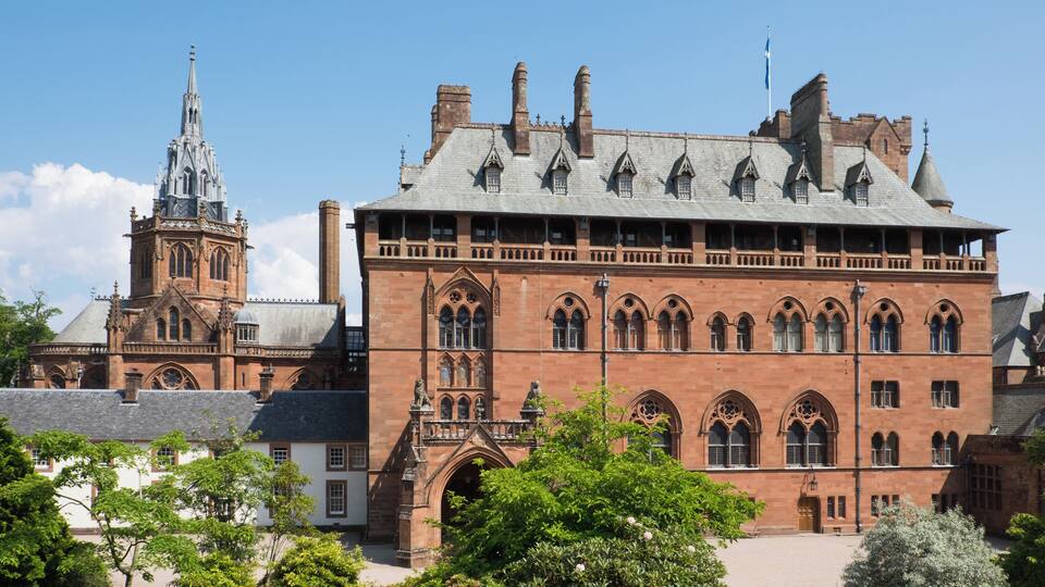 A historic building with a prominent tower and a large courtyard surrounded by trees.