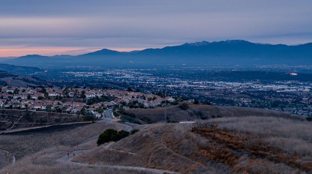 Aerial view of open rolling hills in suburban Southern California. Radio tower atop hill during sunset surrounded by mountains and ocean