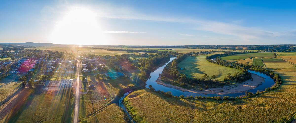 A river winding through a rural landscape with fields and a small village.