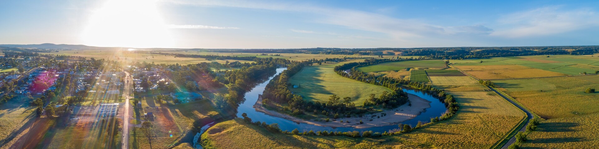 A river winding through a rural landscape with fields and a small village.