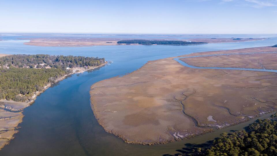 A river winding through a landscape with patches of water, land, and dense forests.