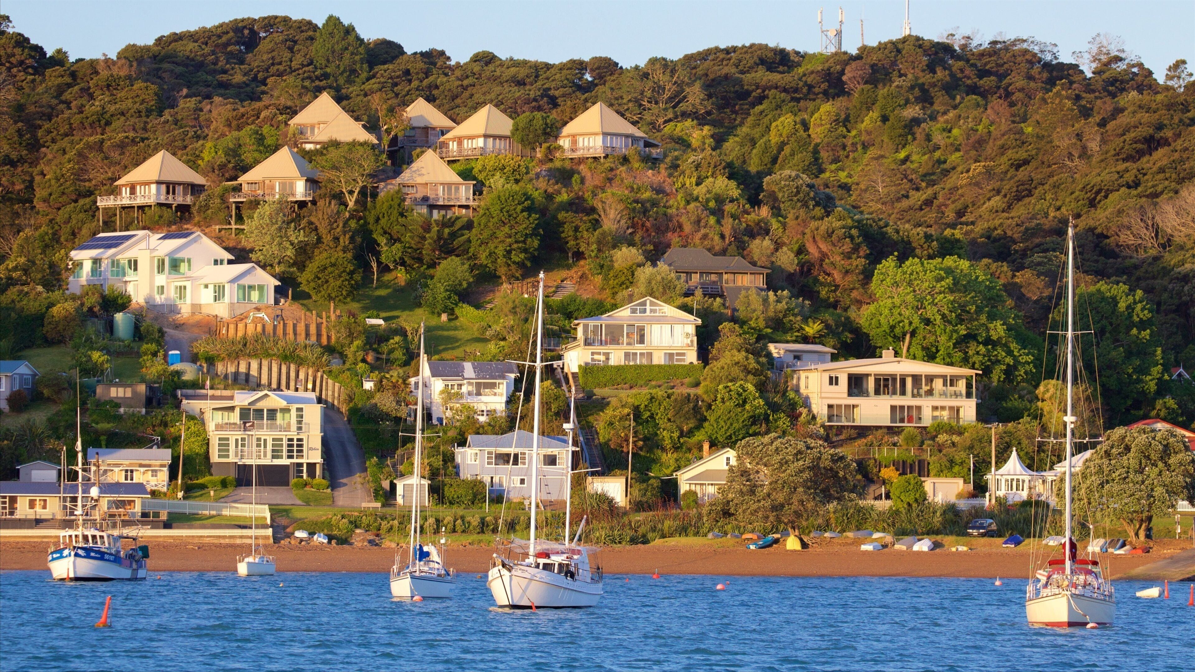 A coastal village with houses on a hillside, boats on the water, and a sandy beach.