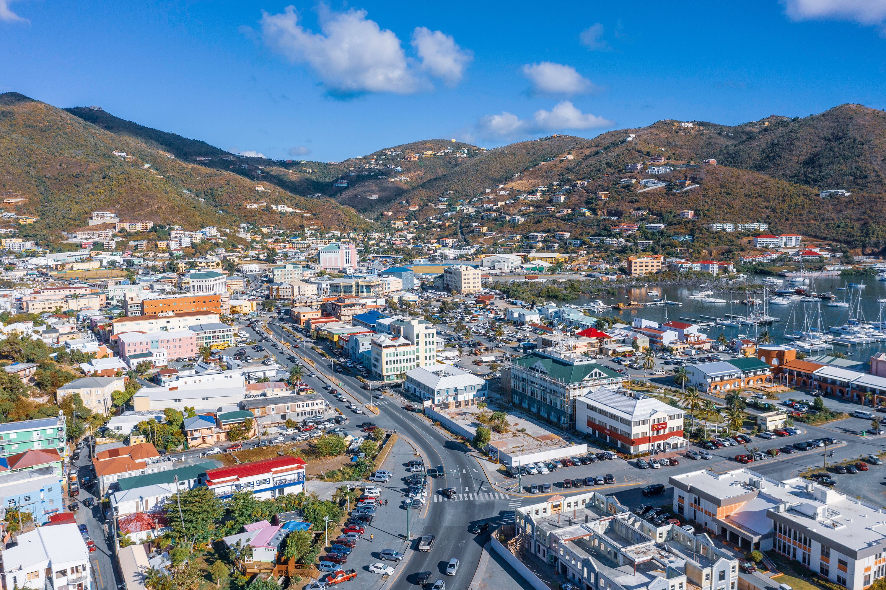A coastal town with a marina, hilly backdrop, and dense urban buildings.