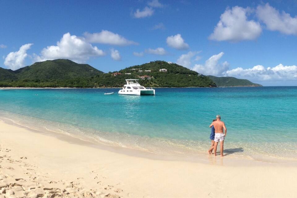 A beach with a boat and a person walking on the shore.