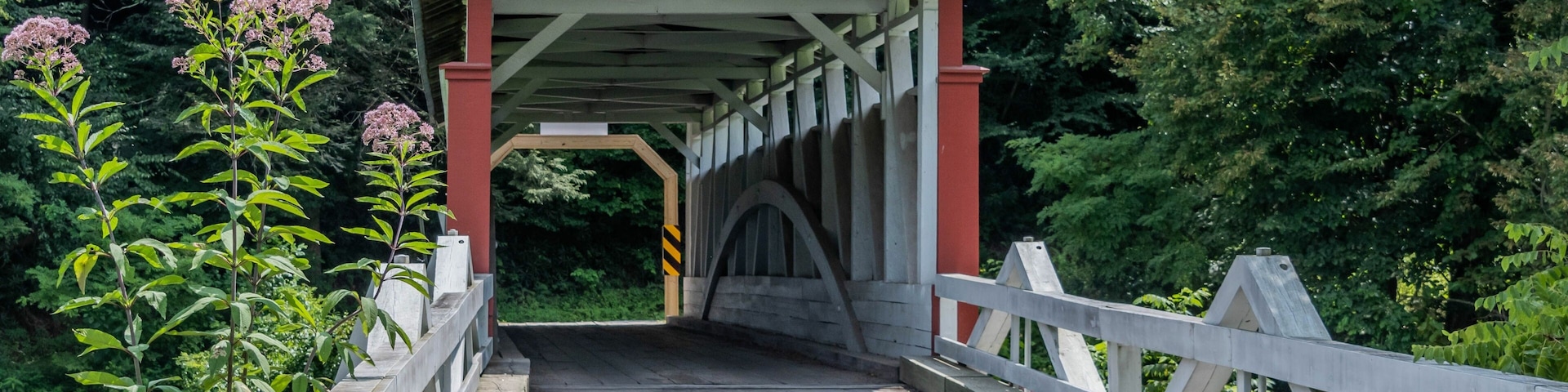 A covered wooden bridge with a sign indicating a $5 fine for riding or driving over it faster than a walk.
