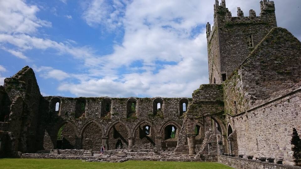 A historic stone castle with ruins and a grassy courtyard.