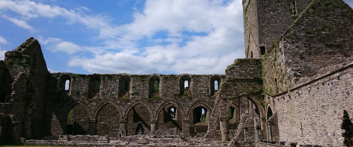 A historic stone castle with ruins and a grassy courtyard.