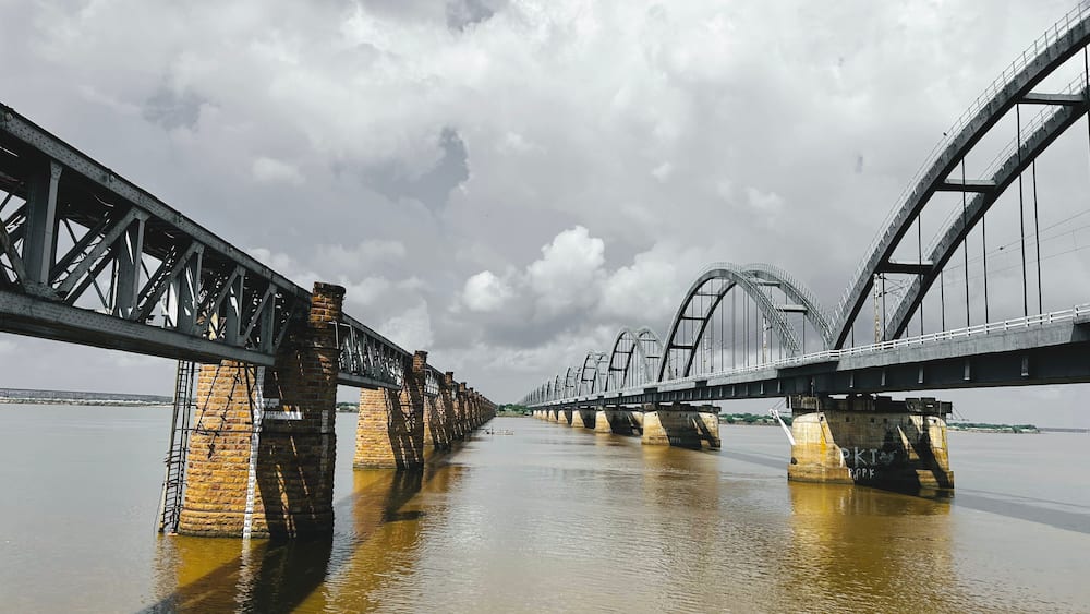 A large steel bridge over a river with brick piers.
