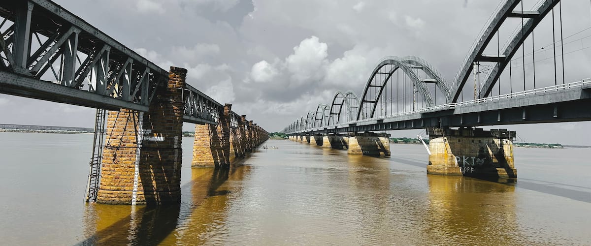 A large steel bridge over a river with brick piers.