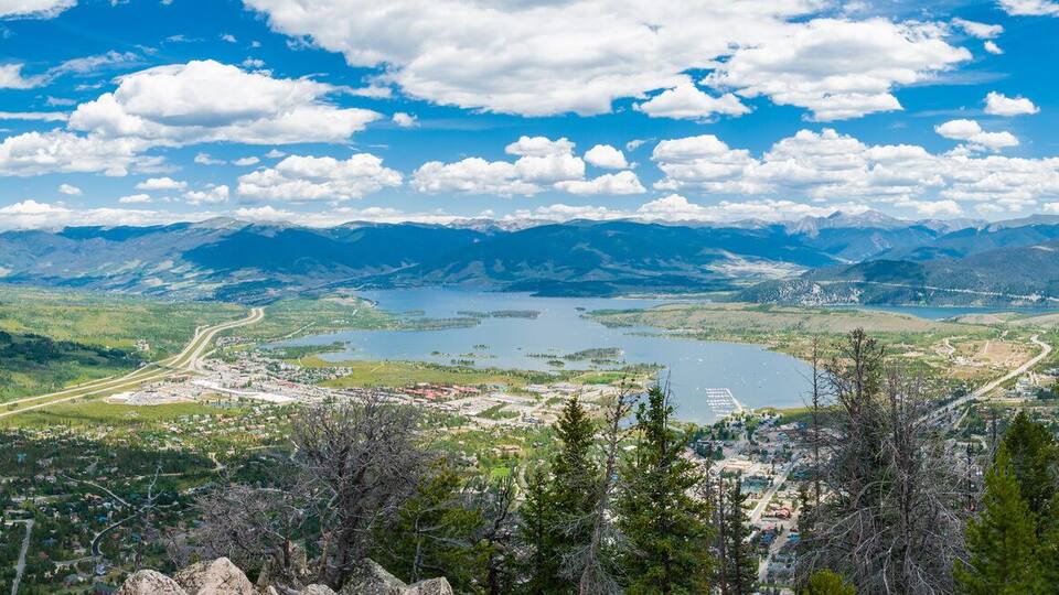 A mountainous landscape with a river, a town, and a highway.
