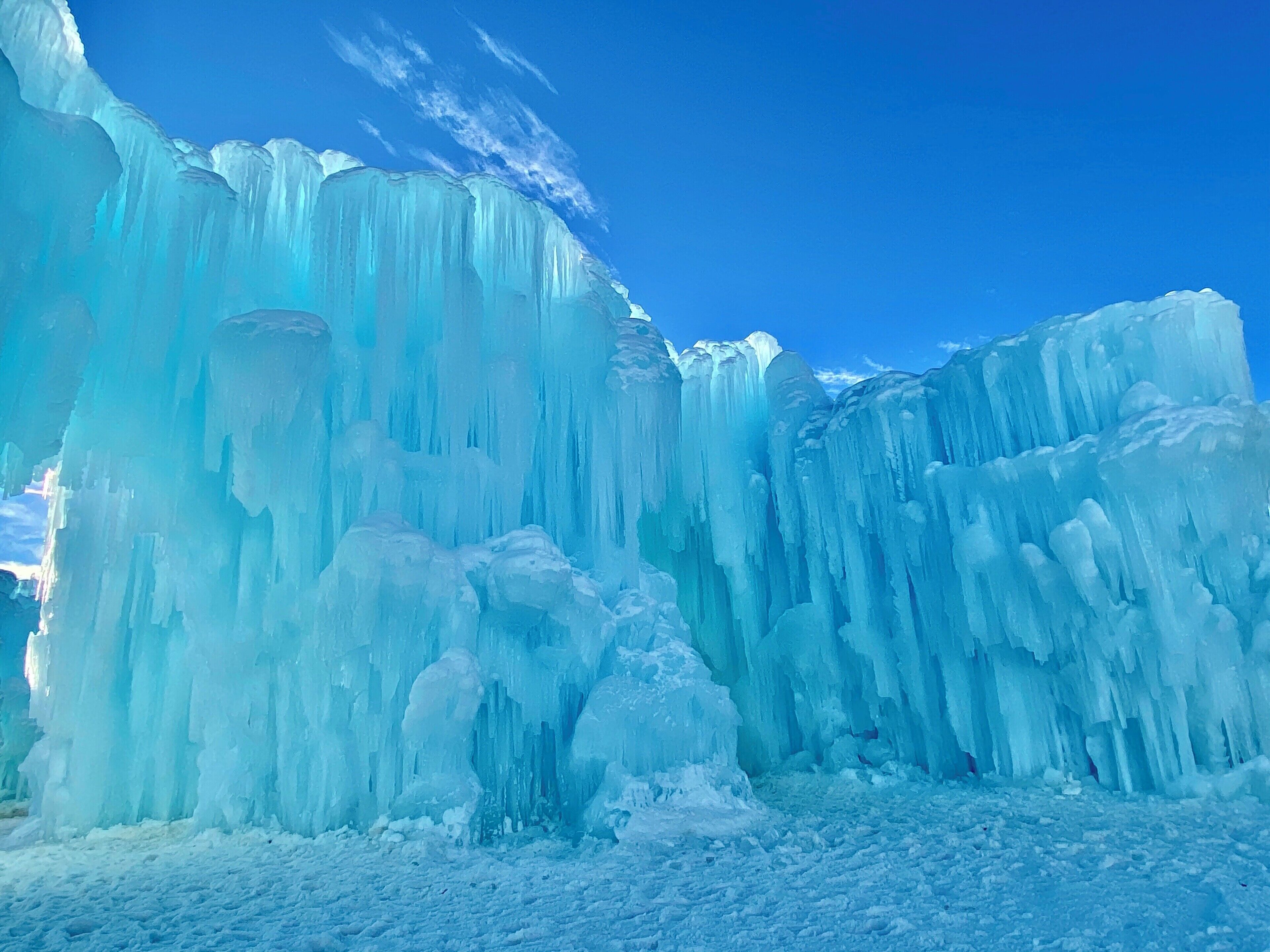 A large ice formation with tall, vertical ice columns and a clear blue sky in the background.