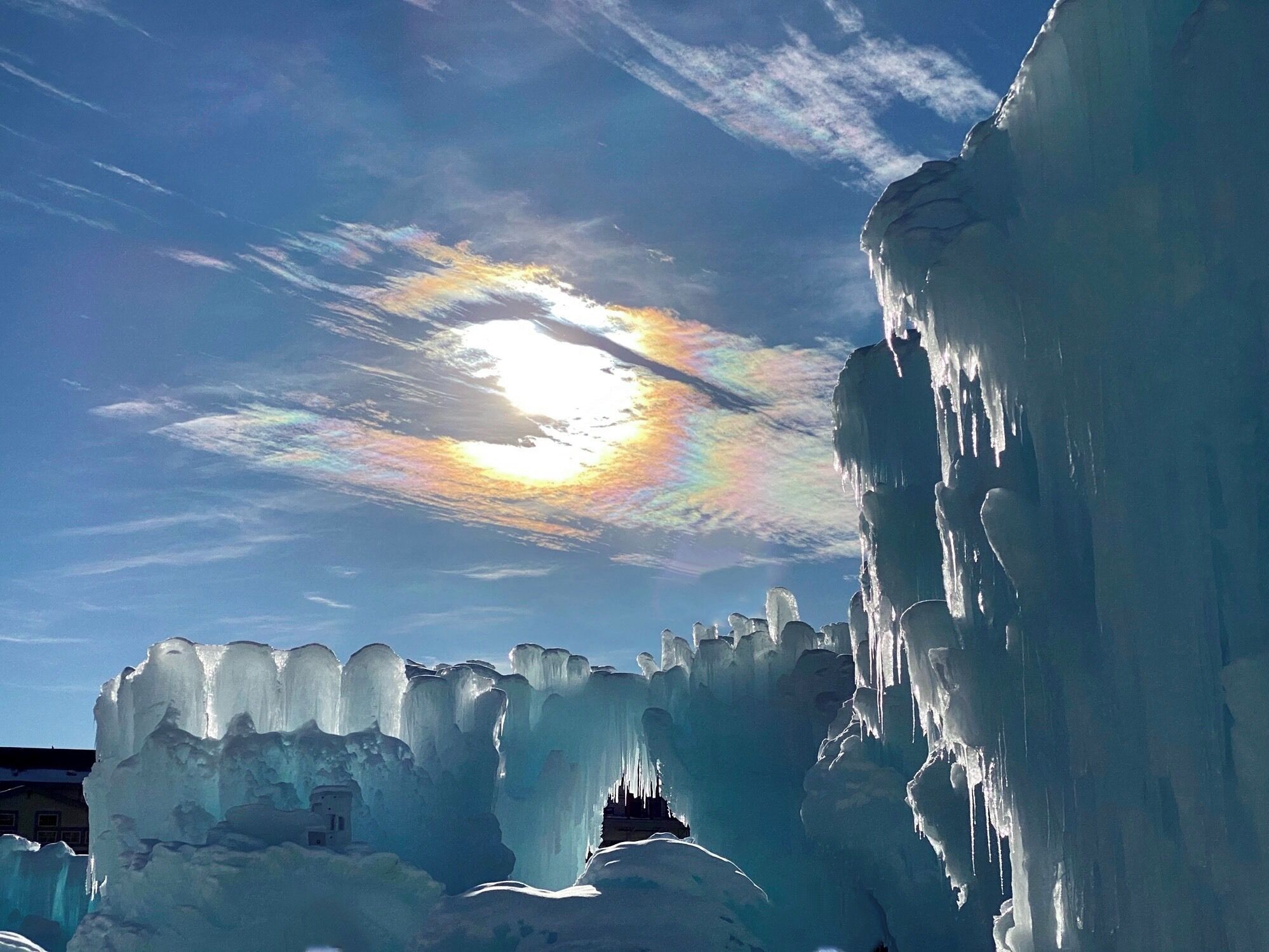 A large ice formation with a small building in the background.