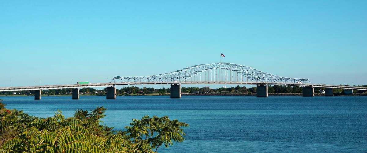A large bridge spanning a river with a flag on top.