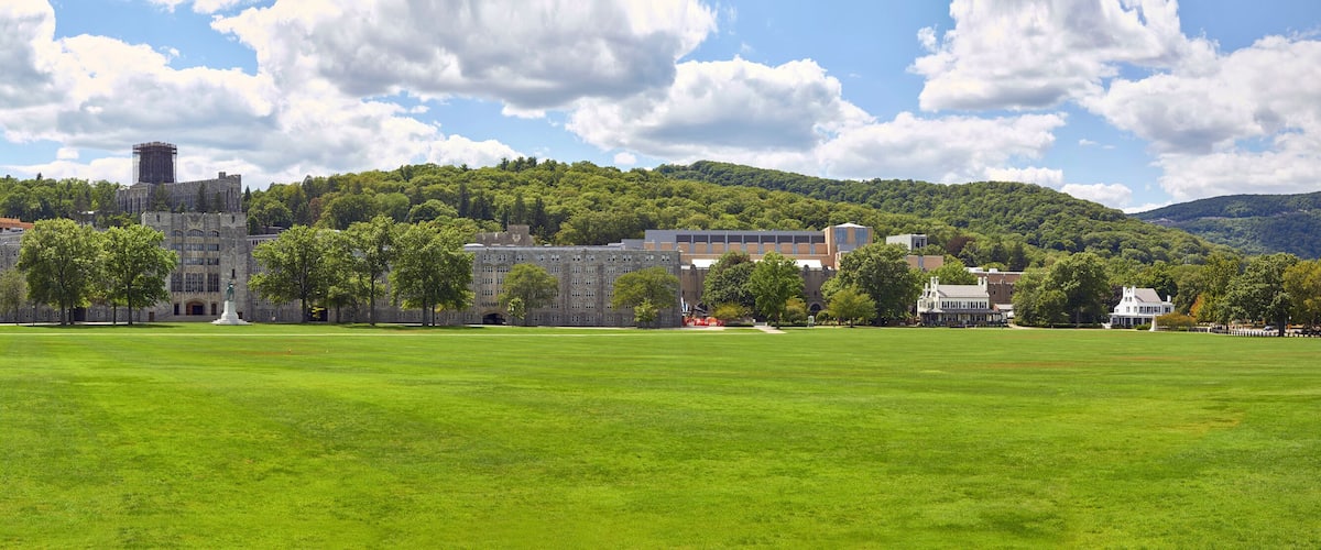 A large green field with historic buildings and a castle on a hill.