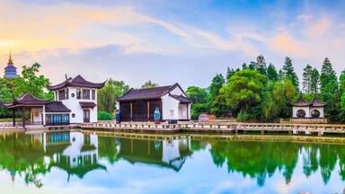 A traditional Chinese garden with a pond, pagoda, and classical architecture.