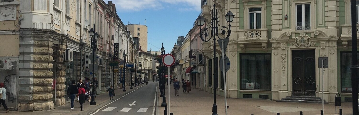 Calle con edificios históricos, cielo despejado y señal de prohibido el paso.