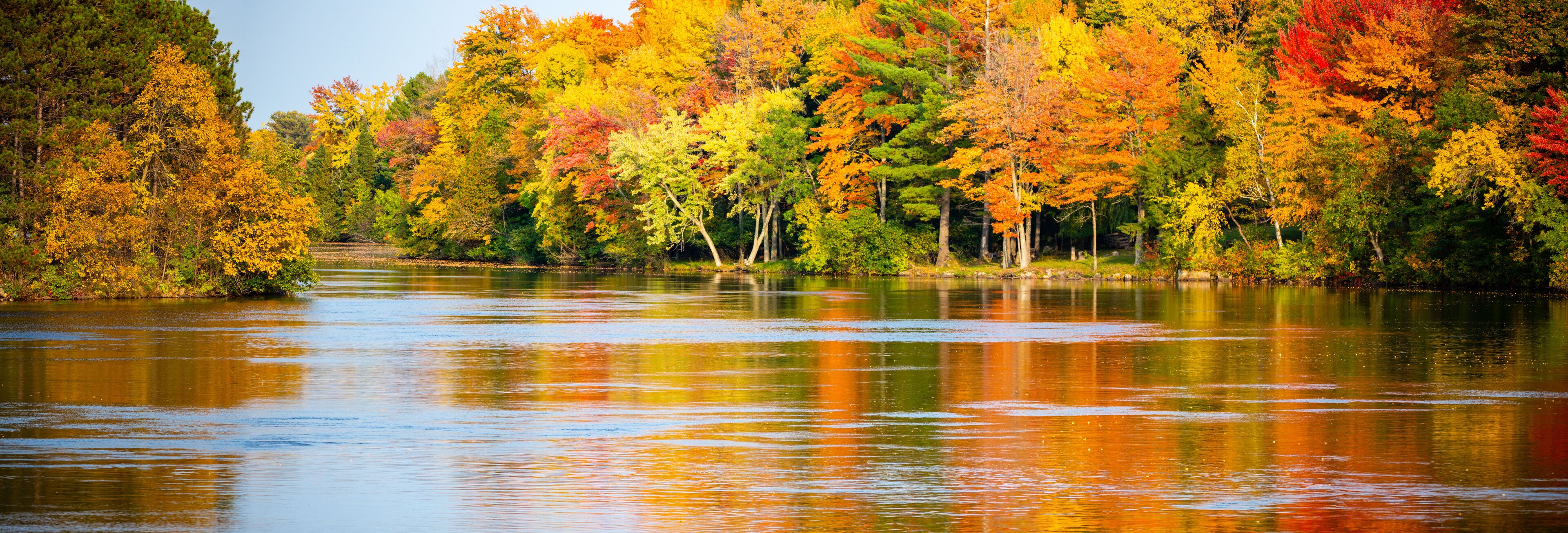 A river reflecting colorful autumn foliage.