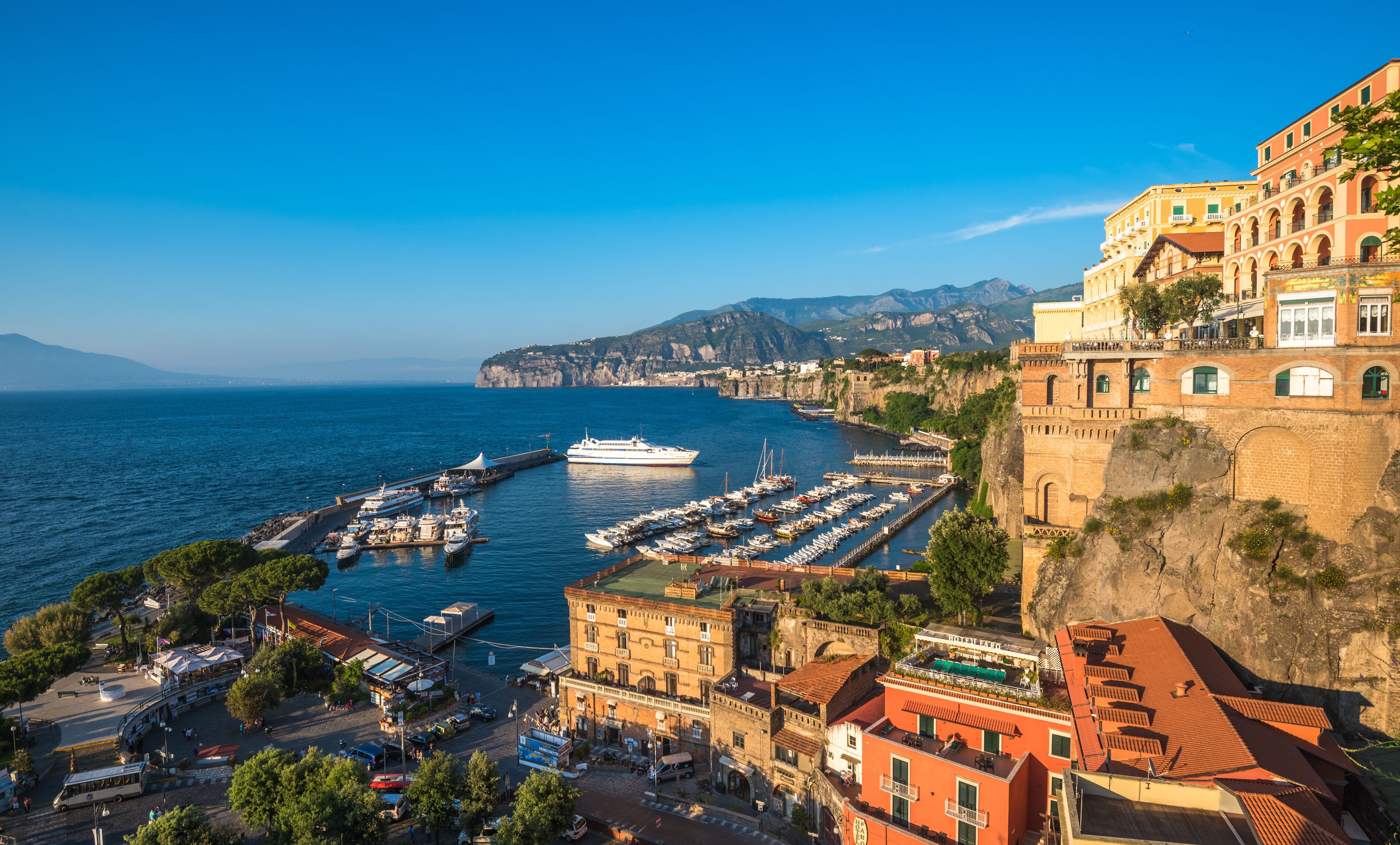 A coastal town with a marina, historic buildings, and a cliff overlooking the sea.