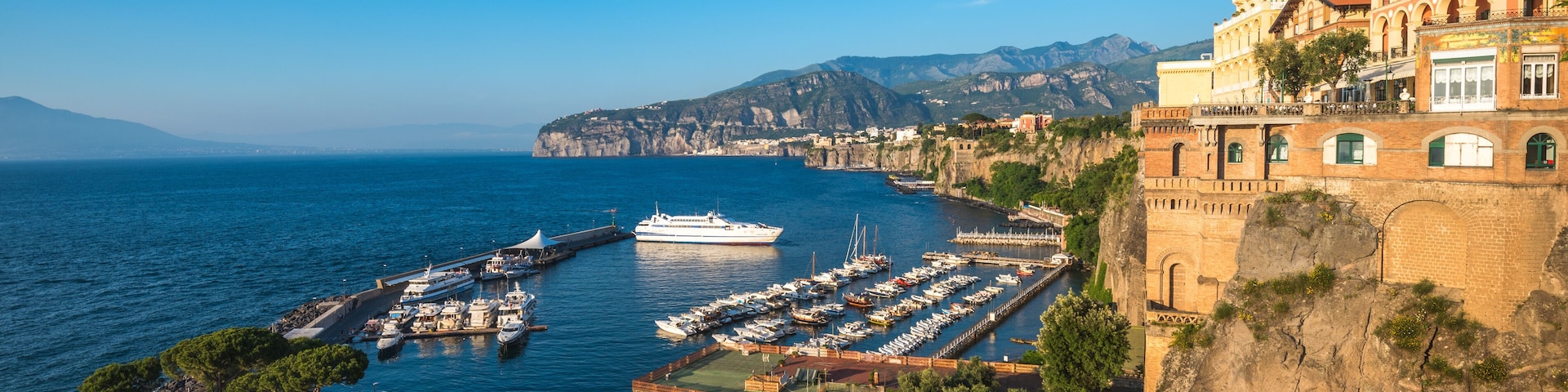 A coastal town with a marina, historic buildings, and a cliffside.