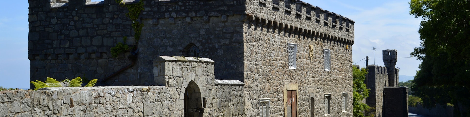 A stone castle with an American flag, a clear sky, and a road in front.