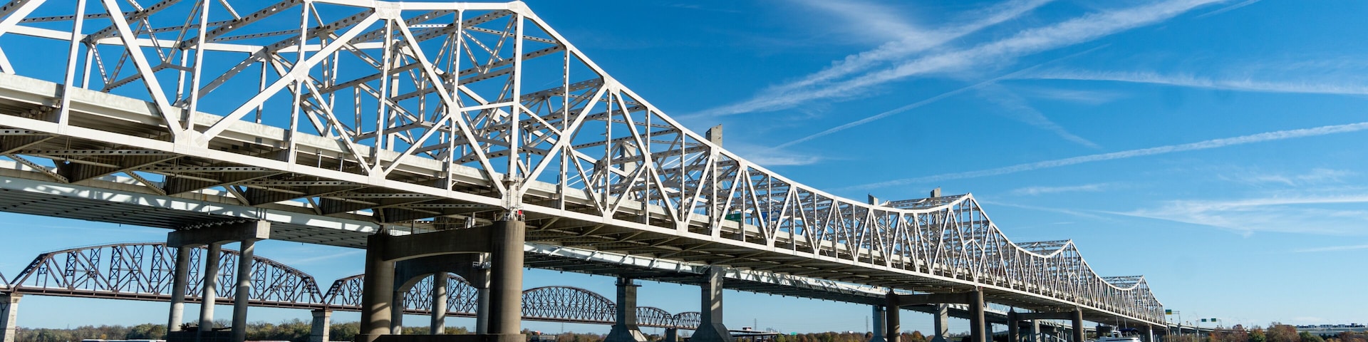 A steel bridge spanning a river with a clear blue sky above.