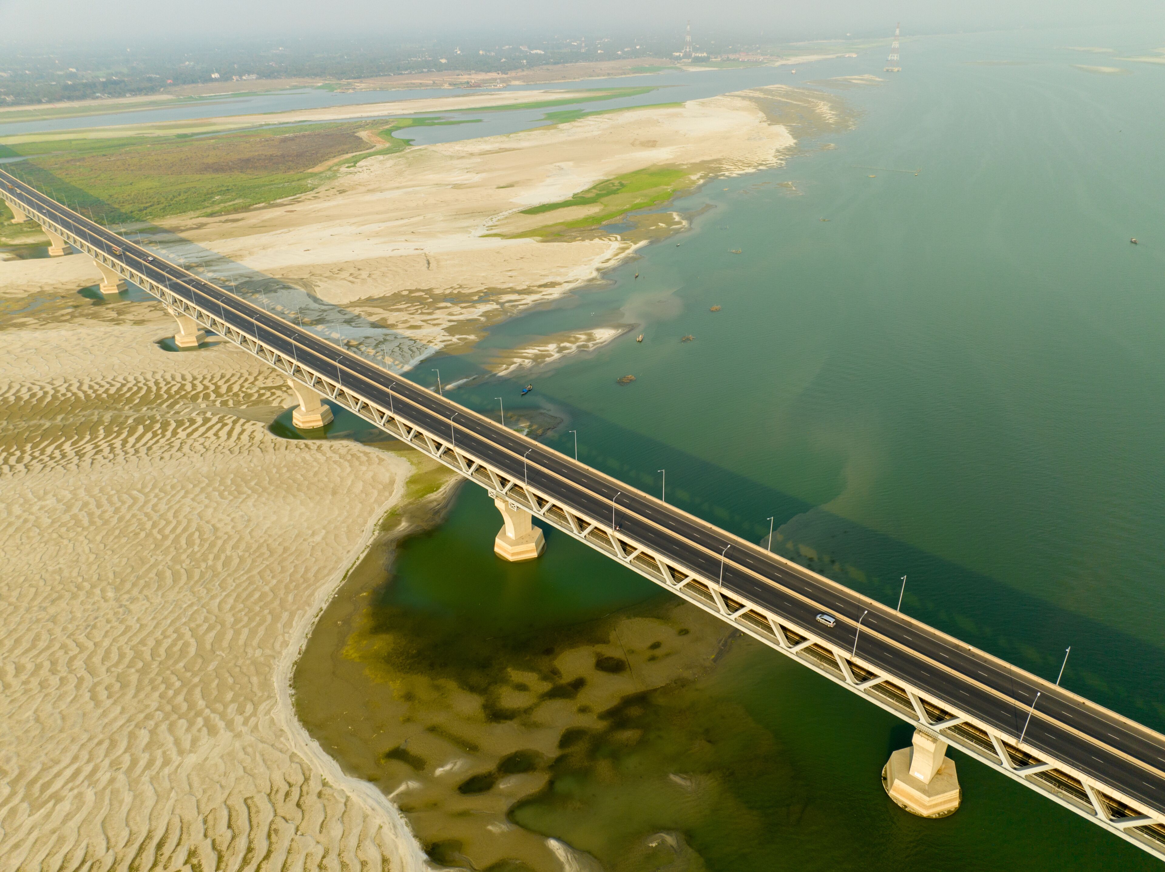 Aerial view of a bridge stretching across the river with sandbanks under a hazy sky, Mawa, Dhaka Division, Bangladesh.