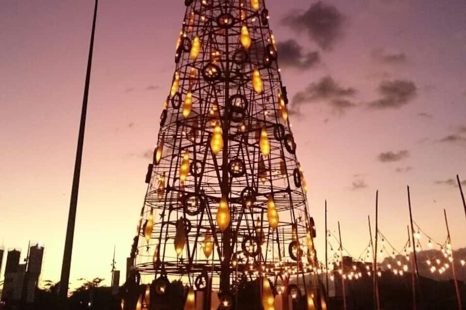 A large, illuminated Christmas tree structure at dusk.