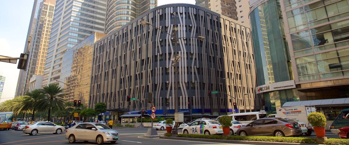 A modern urban street with tall buildings, including a distinctive curved structure with vertical lines.