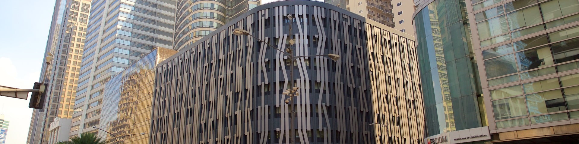 A modern urban street with tall buildings, including a distinctive curved structure with vertical lines.