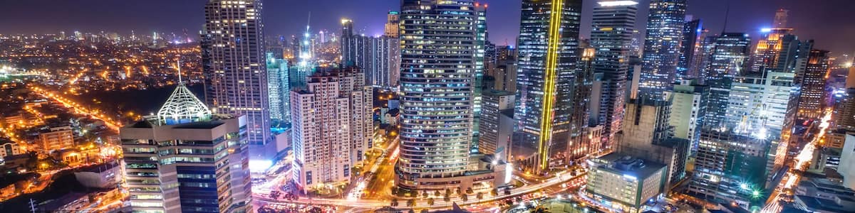 A cityscape at night with illuminated skyscrapers and a busy intersection.