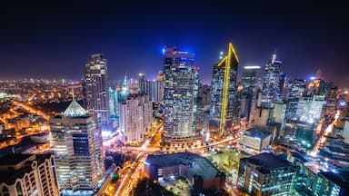A cityscape at night with illuminated skyscrapers and a busy intersection.