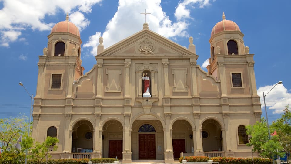 A church with two domes, a central cross, and a statue of Jesus.