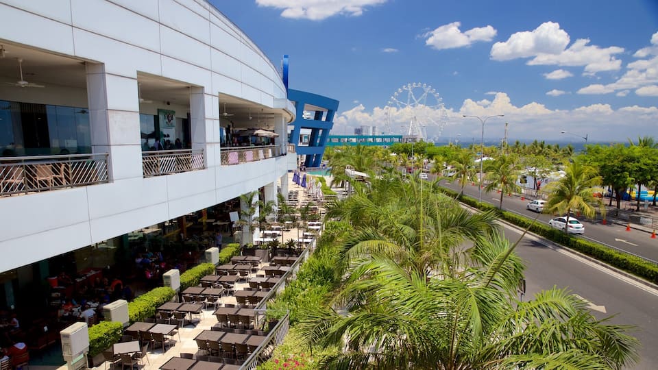 A modern building with outdoor seating and a Ferris wheel in the background.
