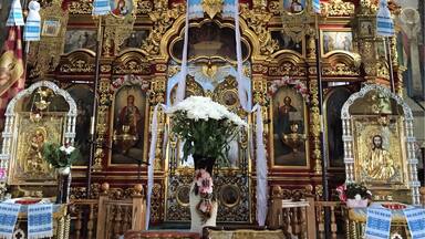 An ornate religious altar with golden decorations, religious paintings, and a central white floral arrangement.