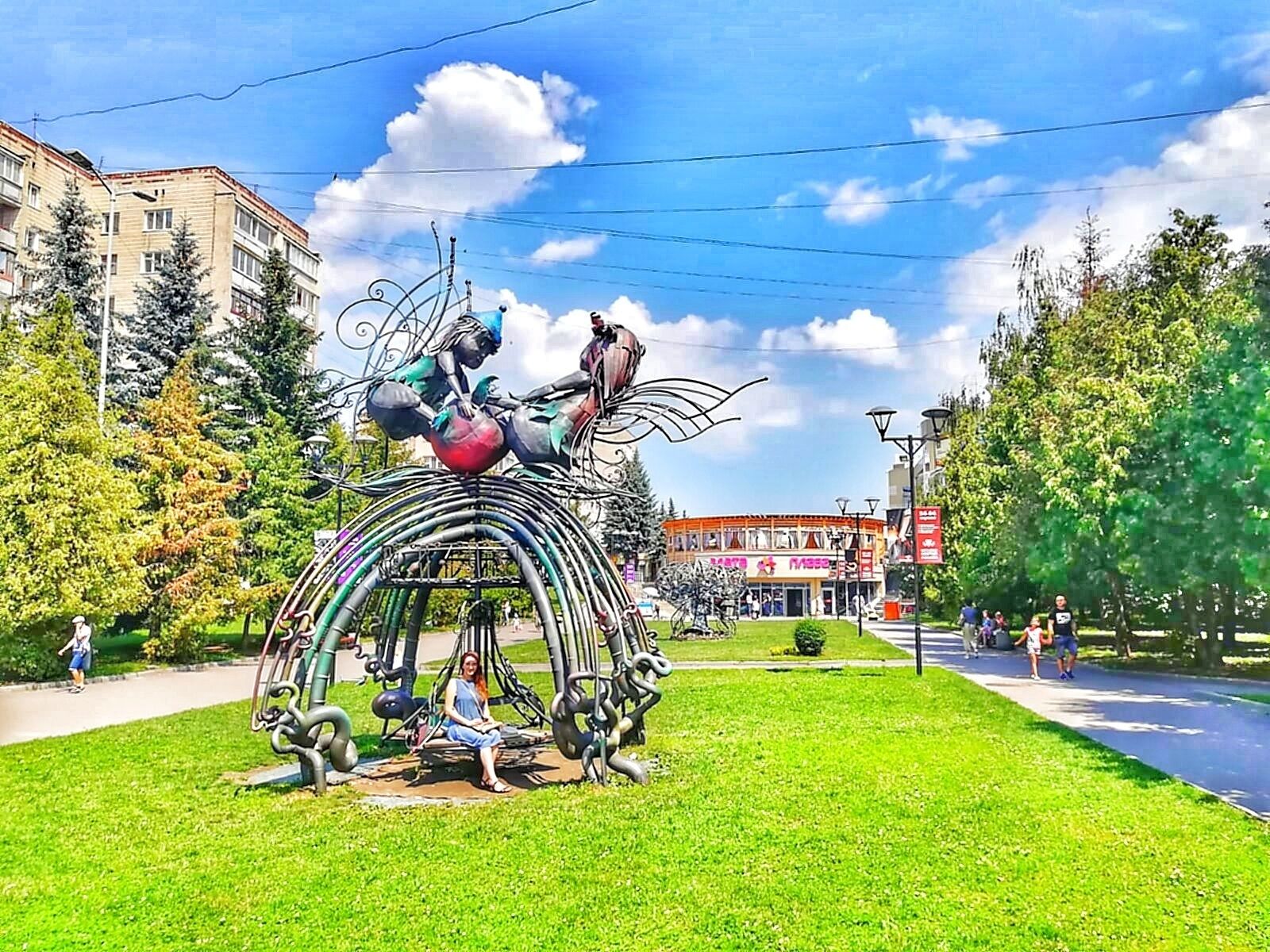 Una escultura en un parque, con un edificio al fondo.