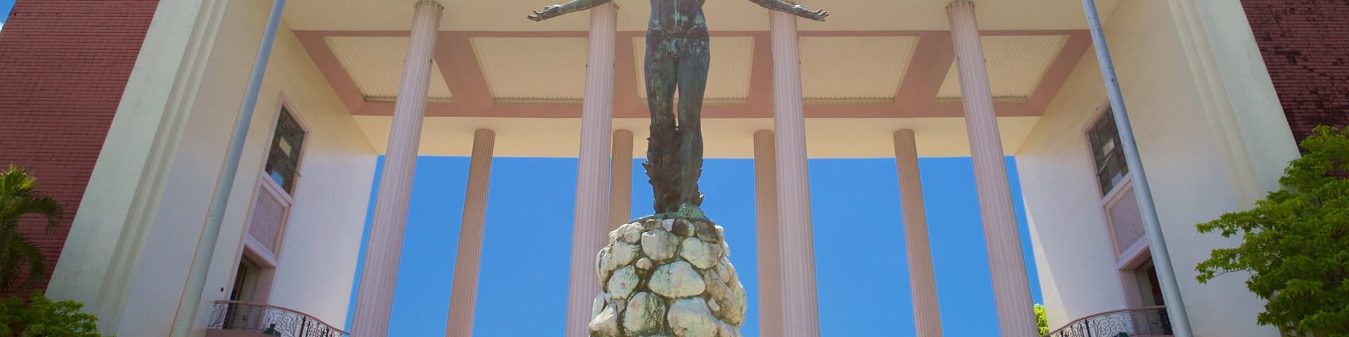 A statue in front of a building with columns and flags.