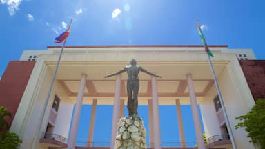 Uma estátua em frente a um edifício com colunas e bandeiras.