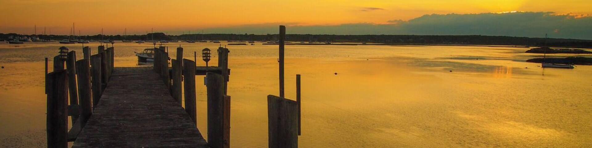 A wooden pier extending into calm water at sunset.
