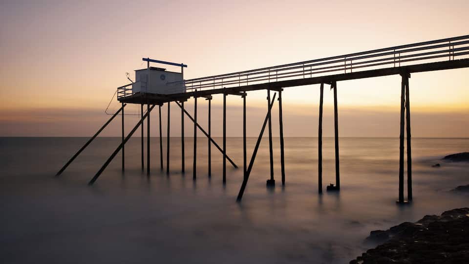 A pier extending into calm waters at sunset.