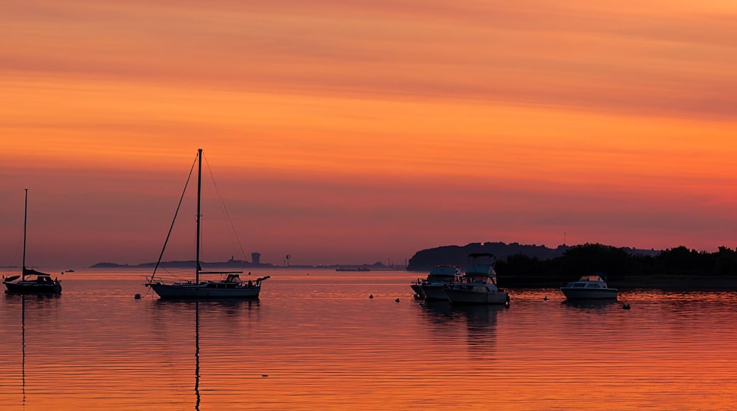 Sunrise behind silhouette sailboats moored on the Neponset River under an orange sky in Dorchester, Boston