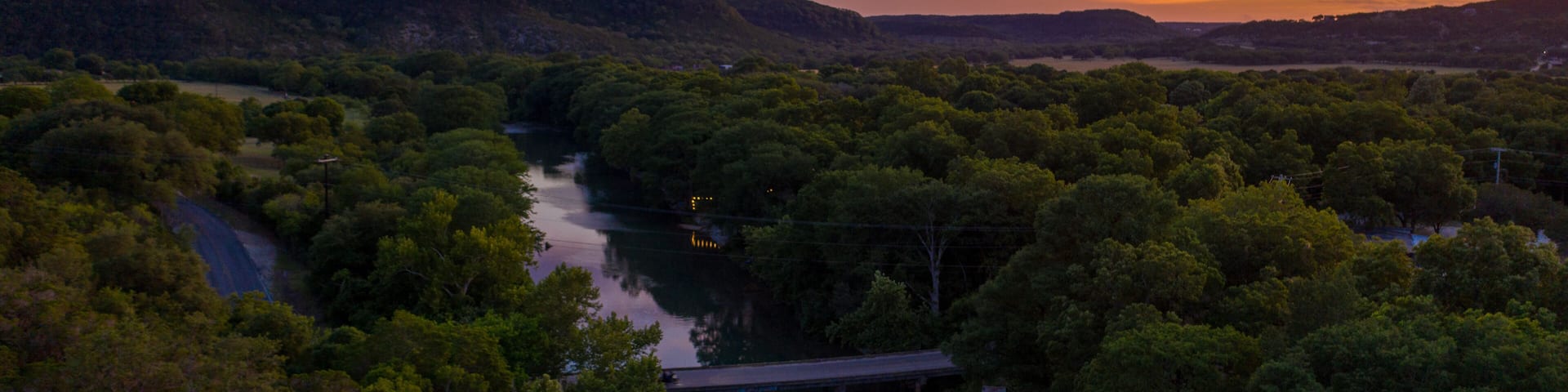 A river winding through a forested valley with a bridge crossing over it.