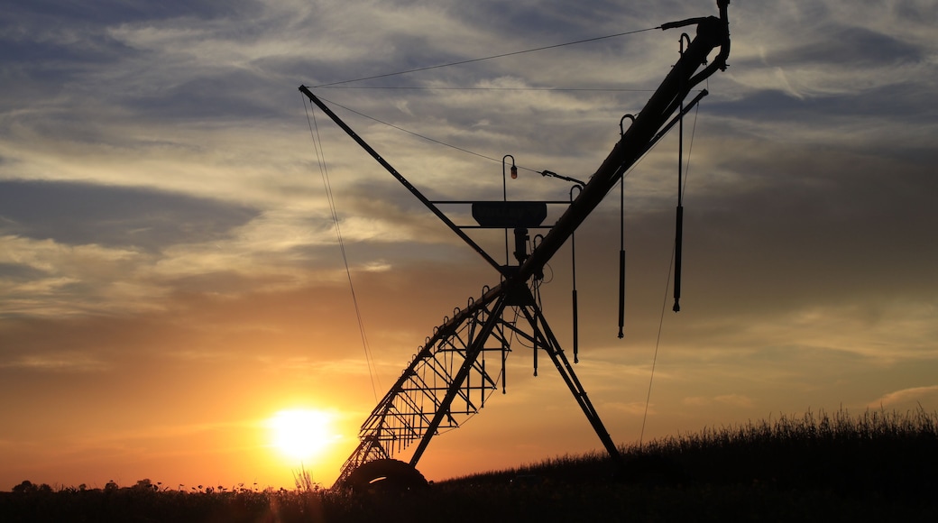 Irrigation System silhouette at Sunset with a colorful sky and clouds with the Sun south of Sterling Kansas USA out in the country.