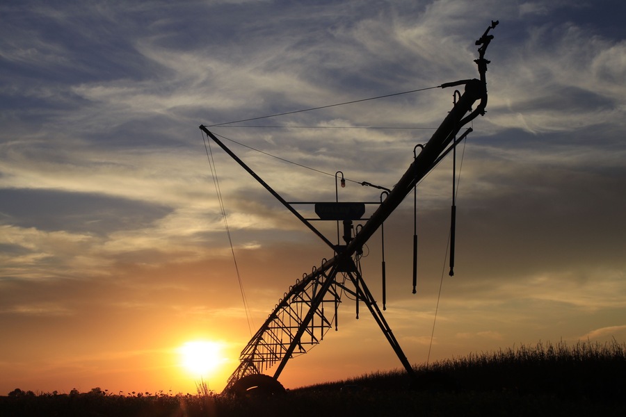 Irrigation System silhouette at Sunset with a colorful sky and clouds with the Sun south of Sterling Kansas USA out in the country.