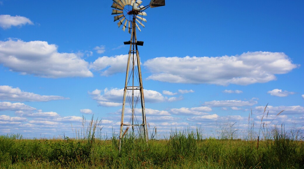 windmill in the field in Kansas west of Sterling Kansas with grass,blue sky, and white clouds.