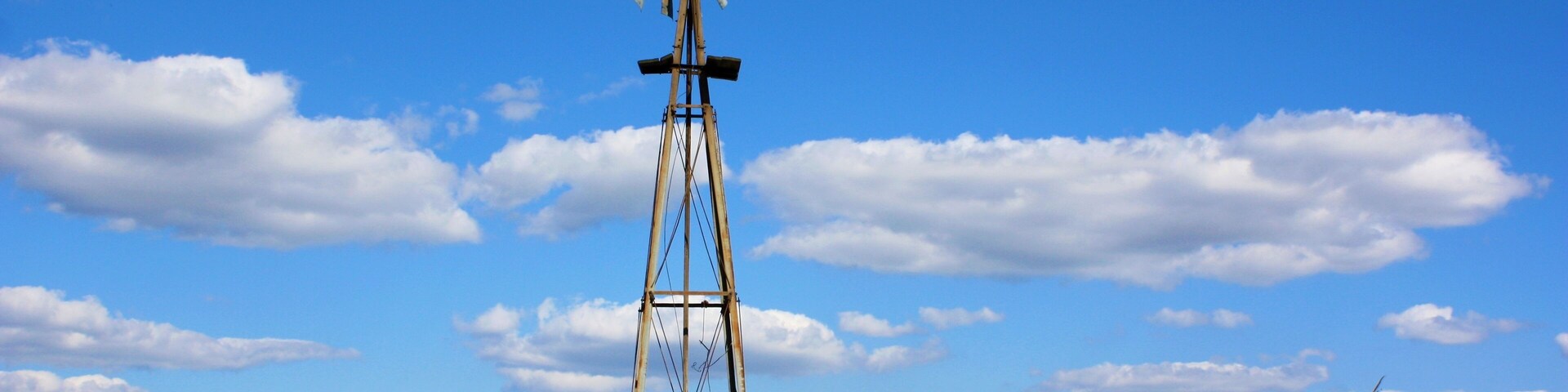 windmill in the field in Kansas west of Sterling Kansas with grass,blue sky, and white clouds.