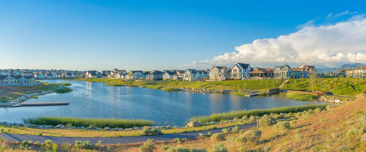 A lakeside residential area with houses, a dock, and a clear sky.