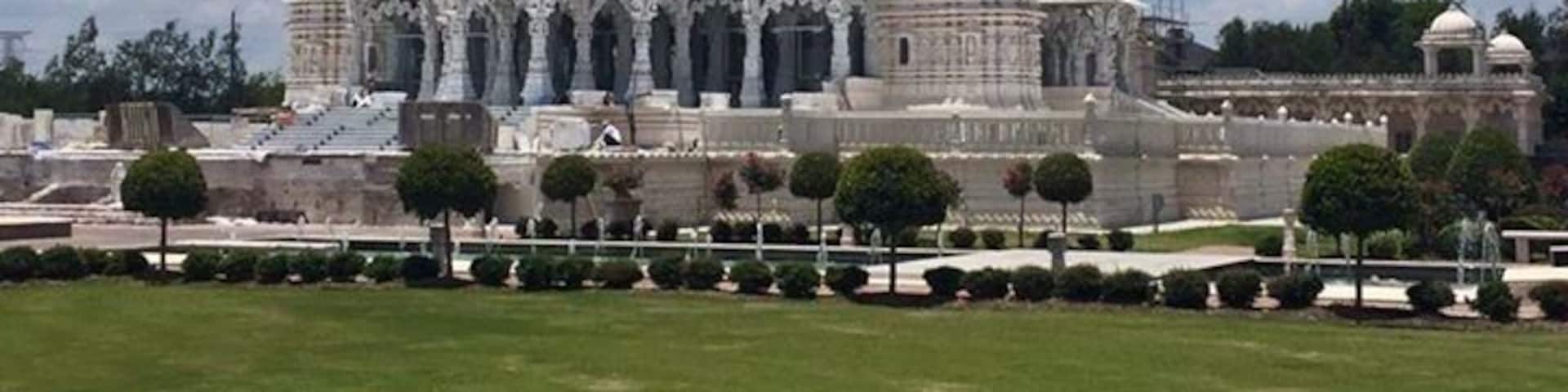 A large white temple with multiple domes and spires, surrounded by a well-maintained garden.