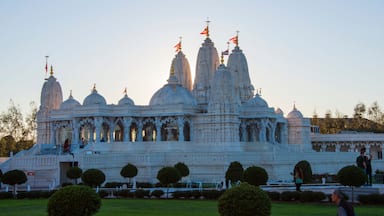 Um templo branco grande com várias cúpulas e torres, rodeado por jardins bem cuidados e caminhos.