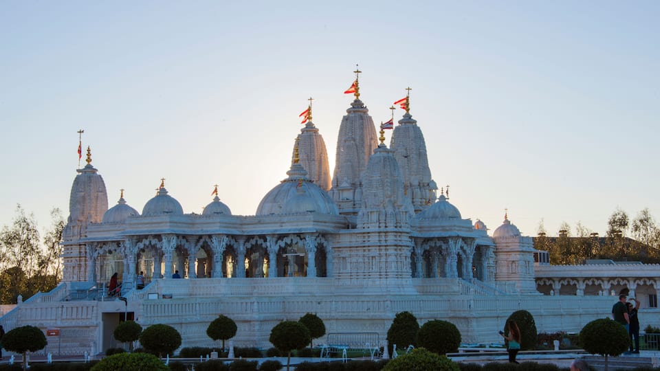 A large white temple with multiple domes and spires, surrounded by well-maintained gardens and pathways.