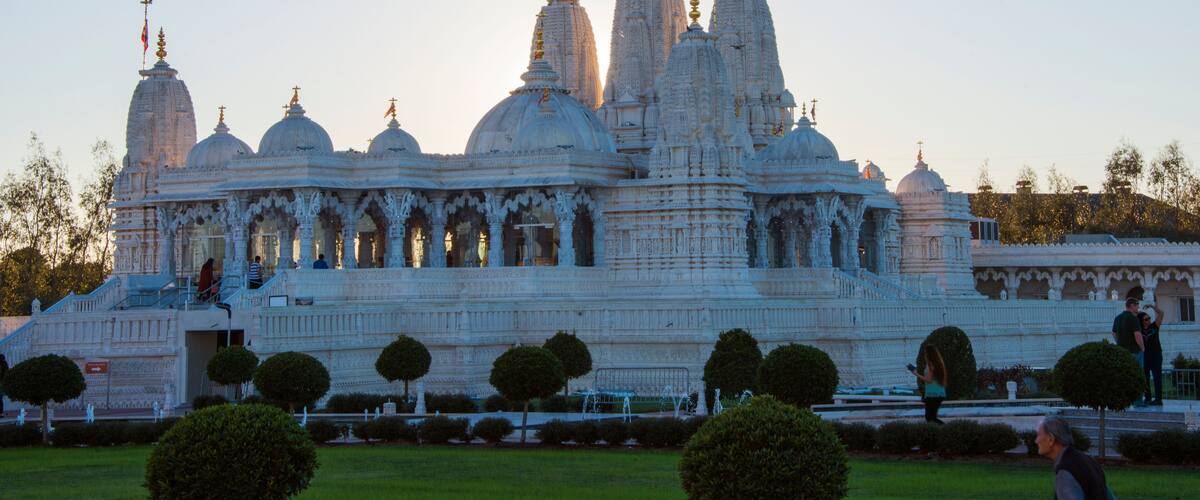 A large white temple with multiple domes and spires, surrounded by well-maintained gardens and pathways.